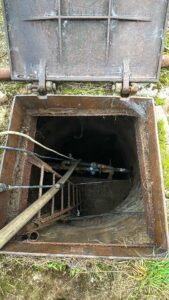 Průmyslová studna u Agro-Družstva Těmice před odborným čištěním – dno pokryté silnou vrstvou bahna a písku, omezený přítok vody.